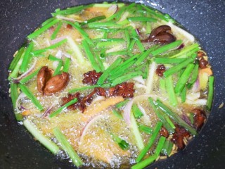 3、香菇牛肉酱,炒锅内倒入菜籽油烧热，下入准备好的小葱、洋葱、生姜、胡萝卜、八角、桂皮、草果和小茴香，小火炸至所有食材微微焦黄。