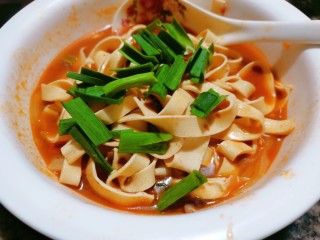 11、水煮千张,煮两分钟后再把千张连汤一起倒入配菜上面,再撒点蒜苗