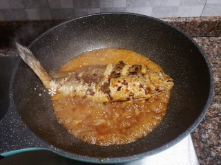 12、酱焖黄花鱼,汤汁收干一半时再将鱼翻面煮。