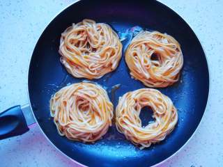 6、鸟巢鸡蛋饼,面条与鸡蛋清搅拌均匀，不粘锅里倒入少量食用油，用筷子把面条围成环形摆放好。