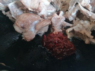 8、啤酒焖羊肉,倒入羊排骨翻炒均匀，加入一勺郫县豆瓣酱。