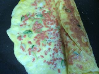 13、火腿葱花厚蛋烧,第二层煎至9.5分熟时，从卷好的第一层蛋卷开始向另一头卷起