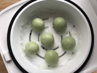 12、酱肉笋丁青团,蒸笼垫上防粘垫，把包好的青团坯子依次放入，待电饭煲中的水沸腾后放入蒸笼，蒸8至10分钟