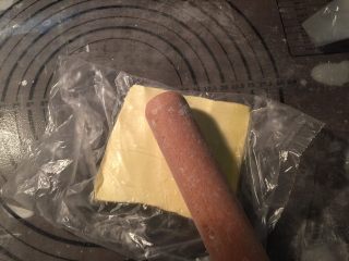 4、流沙起酥包,将片状黄油装入保鲜袋，用擀面杖压成薄片后，放入冰箱冷藏至硬