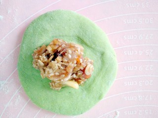 11、青苹果乐园,取一个剂子搓圆,再把它按压成中间厚周边薄的面皮,再放上五仁馅料。