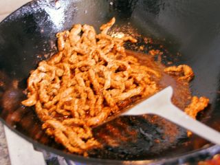 7、京酱肉丝, 倒入炒锅中继续翻炒。