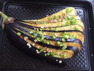7、蒜蓉风琴烤茄,在片与片之间夹入蒜末和青椒丁。烤箱预热上下火175度。放入烤箱烤