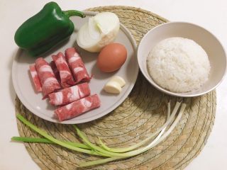 1、肥牛炒饭,备好食材，肥牛片5片，鸡蛋1个，圆青椒1个，洋葱半颗，蒜2瓣，小葱1根，米饭1碗，最好是隔夜饭，如果是刚做好的米饭，一定少加点水，把饭做得干硬一些