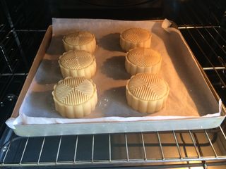 16、广式冰皮蛋黄月饼,烤箱预热10分钟,上下火200度先烤10分钟,拿出来放至微热,鸡蛋黄加入几滴水搅拌均匀,在月饼刷上一层蛋黄液,烤箱温度上火转180度,下火165度,烤10分钟即可。