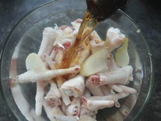3、早茶必点的菜——虎皮凤爪,加入没过鸡爪的冷水，倒入料酒，放入2片姜，浸泡2个小时，浸泡好后再用水冲洗一次，沥干水；