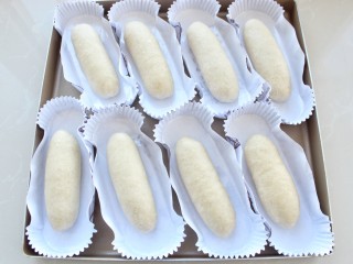 8、热狗面包,将整理好的面团放入纸模中,没有纸膜的可以直接排放烤盘内,注意中间要留一定的空隙,以免发酵后体积变大粘连到一起