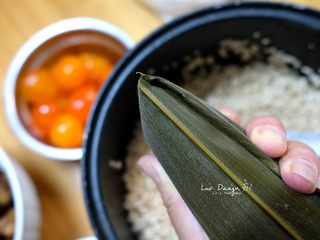 4、吉祥三宝粽（咸蛋黄 五花肉 栗子）,顶部多余的粽叶折叠握紧。