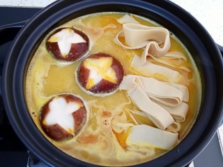 6、咖喱菌菇蔬菜火锅,先下入香菇和豆腐皮煮五分钟左右。