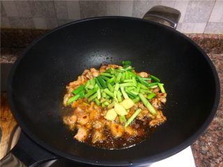 6、蒜苗盐煎肉,放入蒜苗头和生姜片翻炒片刻。