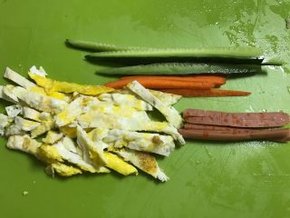 1、快手紫菜包饭,将所有材料准备好，鸡蛋打匀煎皮切条，黄瓜切条，胡萝卜切条，火腿切条。