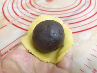 9、广式豆沙蛋黄月饼,取一块饼皮，用大拇指把中间压扁，加入一份馅料，用虎口一点点把饼皮慢慢地推上去