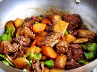 11、土豆炖牛仔骨,还有一点汤汁的时候最后再放入青椒翻炒均匀即可完成。