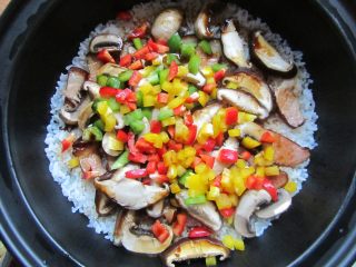 11、腊肉煲仔饭,等到蜂鸣器再次响起，显示“b”时迅速倒入彩椒粒，加盖再焖5分钟