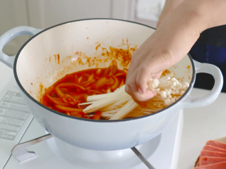 4、部队火锅,向锅中放入洗净去根的金针菇