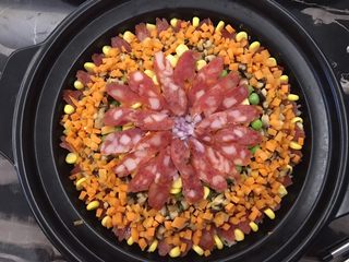 9、腊肠砂锅煲仔饭,再一次码入食材，焖煮的时候，食材的味道都会融合在一起的，最后也都要搅拌在一起的，所以随意摆