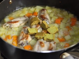 10、咖喱鸡翅,关上火，取出咖喱块，切成小块放入锅中，搅拌至咖喱块完全溶解。接着开微火继续炖煮5分钟至咖喱呈稠糊状。中途翻锅。