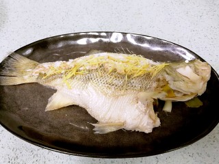 12、粤式清蒸鲈鱼,鱼蒸好后取出，倒去盘内浮水，摆上姜丝。