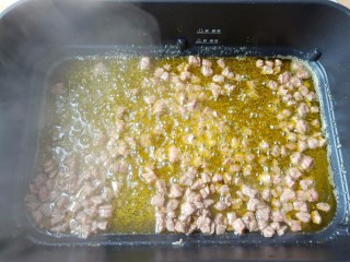 5、万能酱料【香辣牛肉酱】,锅里多加一点菜籽油【用菜籽油炒出来的牛肉酱特别的油光红亮，味道更好】油温五成热加牛肉丁翻炒至变色先盛盘备用。