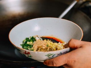 5、老干妈拌面,取出花生，把锅里的热油滴入酱汁中。