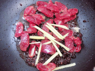 9、蒜苗炒腊肠,放入姜丝翻炒均匀。