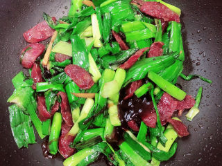 12、蒜苗炒腊肠,放入5克蚝油，继续翻炒均匀。