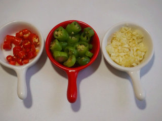 1、凉拌鱿鱼须,将小米辣、青辣椒切成圈；大蒜切碎待用