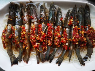 9、蒜蓉粉丝虾,将虾整齐的放在粉丝上并将调好的酱料用小勺舀了放在剪开的虾背里