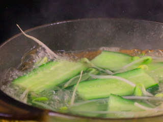 2、川妹子手把手教你做麻辣鲜香味美料足的水煮鱼,黄瓜洗净后切片，和豆芽一起放入开水中焯水