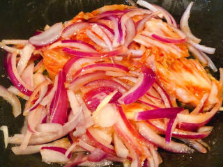 3、部队火锅,锅中倒入底油加热放入洋葱丝爆香再放入辣白菜炒匀