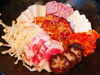 4、部队火锅,洋葱和辣白菜炒至微微变软放入切好的豆腐、午餐肉、年糕、辣白菜、金针菇、羊肉片、金针菇