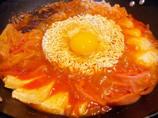 7、部队火锅,煮至食材六成熟放入辛拉面中间再打入一个鸡蛋盖上锅盖继续中小火煮五分钟