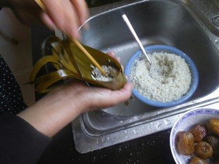8、传统红枣粽,用勺子将少许糯米放在漏斗中，用筷子戳实，然后在放一颗红枣进去