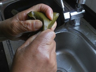 11、传统红枣粽,然后将上方的粽叶折过来，同样也要拉紧一点，然后将剩余的粽叶小尾巴顺着粽子裹一下就可以了