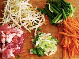 4、薄如蝉翼的春饼,冲洗干净沥干水分后用刀切成段，把胡萝卜也用刀切成细丝备用，小葱用刀切成葱花，把猪肉清洗干净后用刀切成细条状；