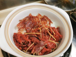 7、广式煲仔饭,饭表面均匀铺上肉肉，加盖小火继续焗7-8分钟。中途要不时移动煲底受热位置，等火力均匀，饭和肉肉焗着味道互相渗透。