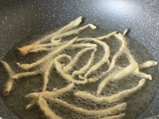 9、椒盐味干炸杏鲍菇,锅里放入油，油温七成热的时候，把菇一条条放入锅中