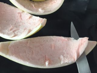 3、清火润肺蜂蜜柚子酱,将刀口紧贴外层表皮（黄色部分）推进，去除内层白色“棉絮”部分；