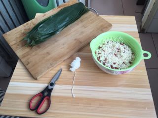 2、红豆粽子,先把粽叶用水烧一个开，沥水备用！糯米和红豆用漏斗的小盆儿沥一下，准备好剪刀，马上就开始啦！