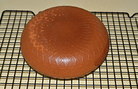 13、海绵蛋糕,烤好后电饭煲会发出蜂鸣提示，将电饭煲内胆从10CM左右的高度向桌面震一下，防止蛋糕回缩，然后将蛋糕倒扣在晾架上晾凉。