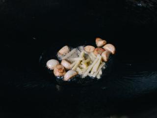 4、干锅花菜,用中火加热油。把蒜瓣炒半分钟。加入姜和辣椒 ，再炒一分钟。