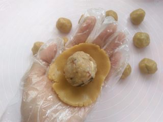 9、清爽五仁月饼,戴上一次性手套,取其中一个面团用2个掌心的摩擦力按扁,放上五仁馅