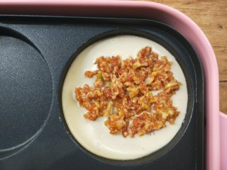 10、复刻街头美食~网厨第一个肉蛋堡,给有面糊的圆盘里,用筷子夹一些已经调好味的肉馅铺在面糊上。