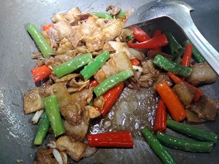 7、虎皮椒香小炒肉,煸香以后倒点适量酱油，料酒，蒸鱼汁鼓油，盐，鸡精。再放入青红尖椒，大火翻炒。