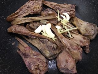 6、食光社劲爆香辣鸭头,煸炒至带皮那面焦黄后，加入姜丝和蒜片