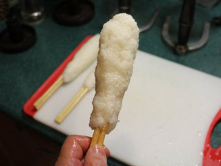 3、烤米卷,将饭团沿竹筷捏成长条型。